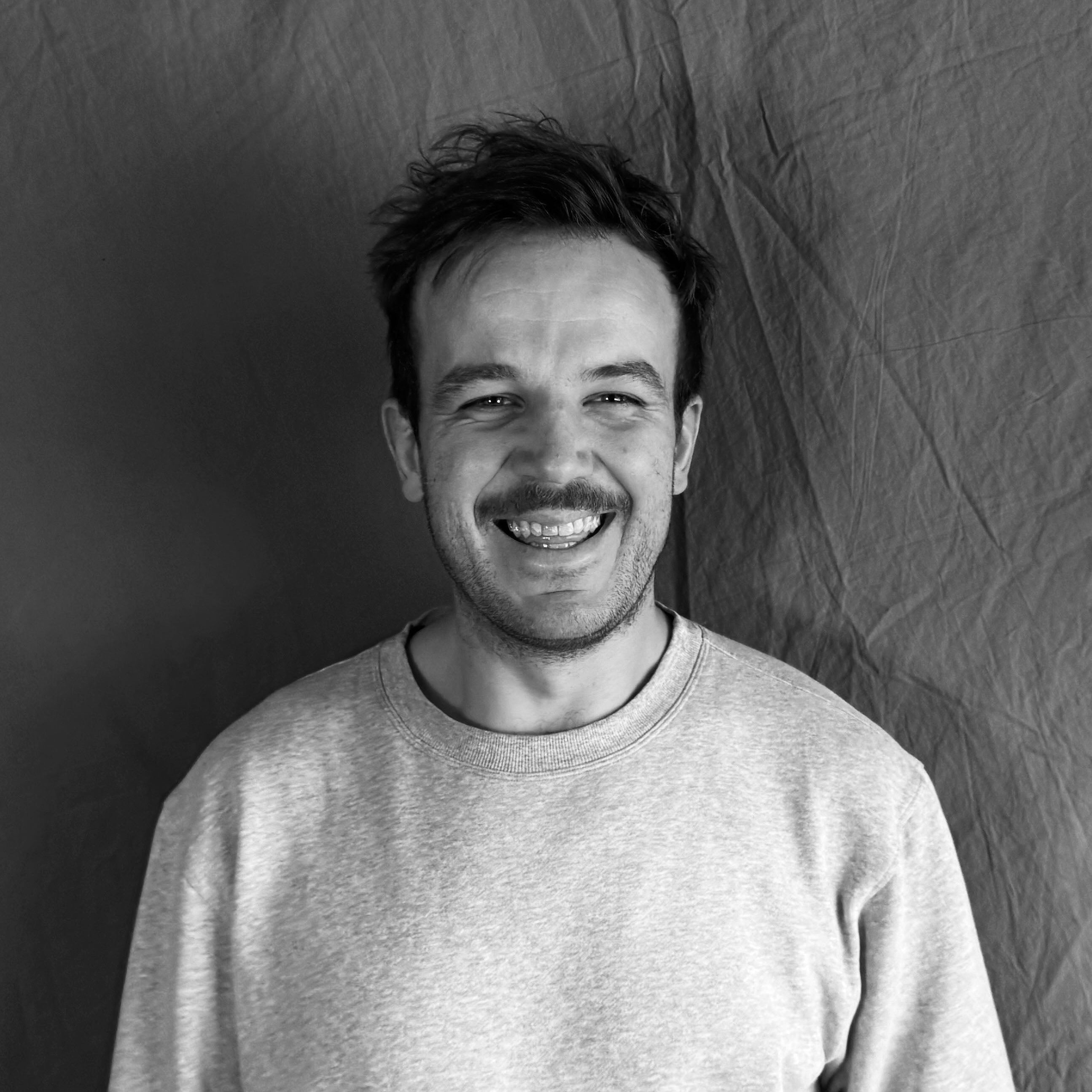 Man wearing a light-colored sweater against a plain background